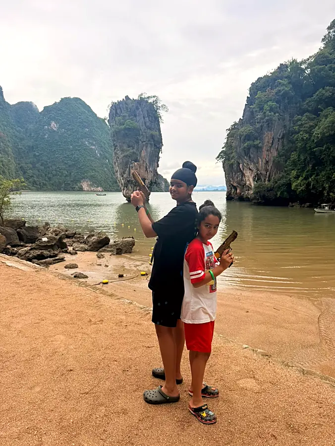 Two of the kids posing back to back on the beach below the limestone cliffs