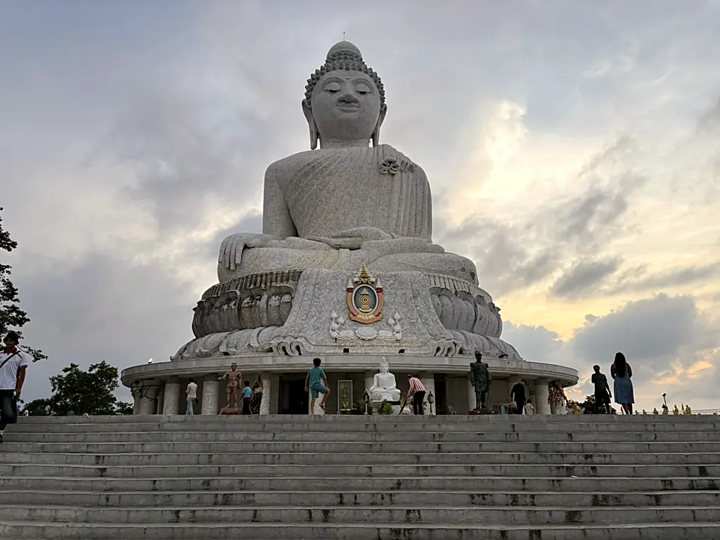 The white marble Big Buddha of Phuket seen from the foot of its steps at dusk