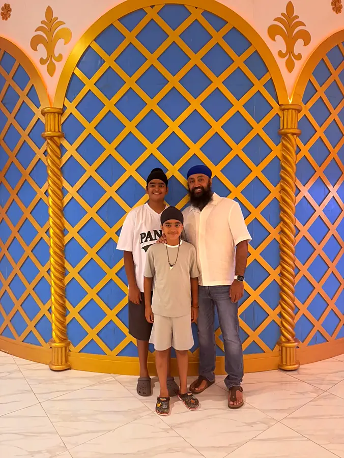 Three of them standing together in front of a blue and gold lattice arch