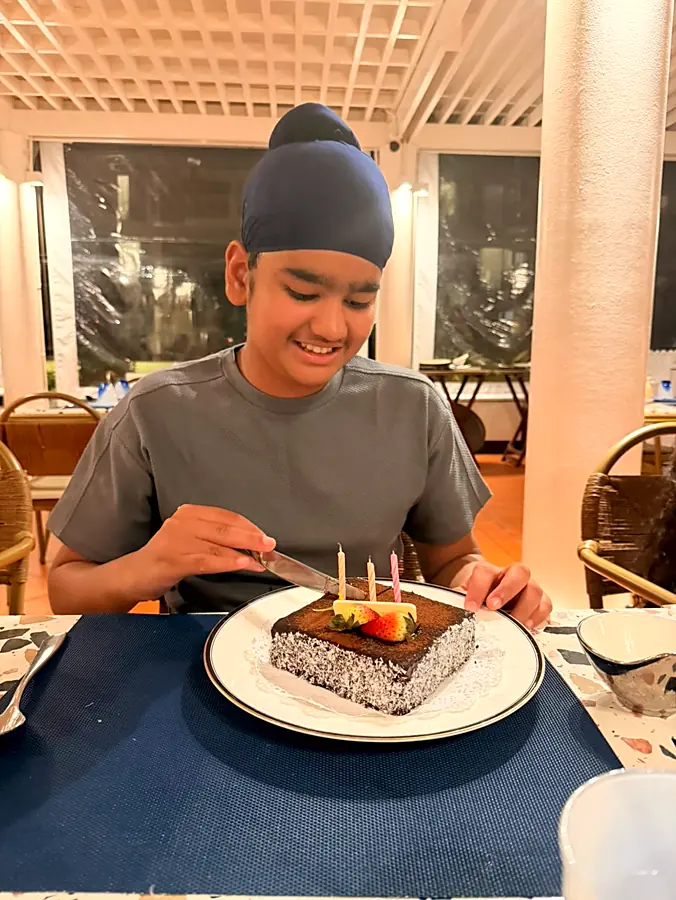 Sitting at a restaurant table at night, knife over a chocolate cake with lit candles