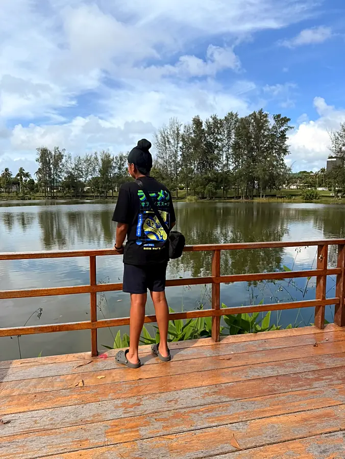 Standing at a wooden rail looking out over the still green lagoon behind the rooms