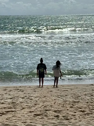 Two of the kids walking down the sand towards a bright silver sea